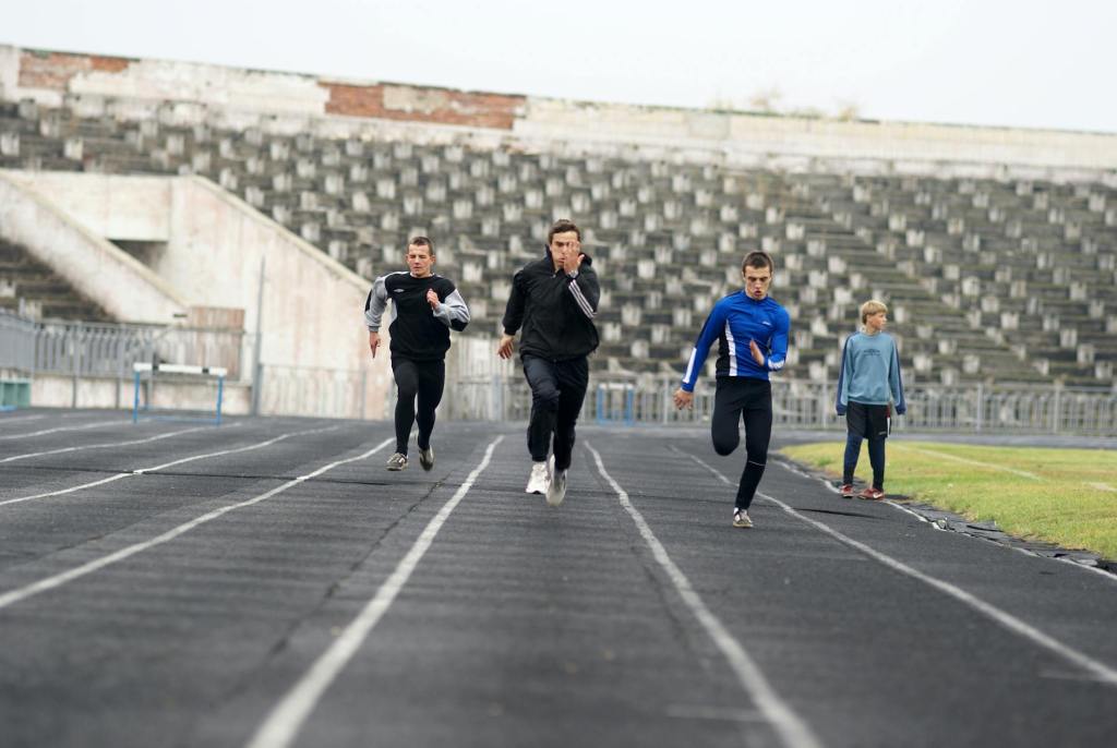 four people running on a track in an empty stadium