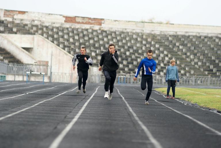four people running on a track in an empty stadium